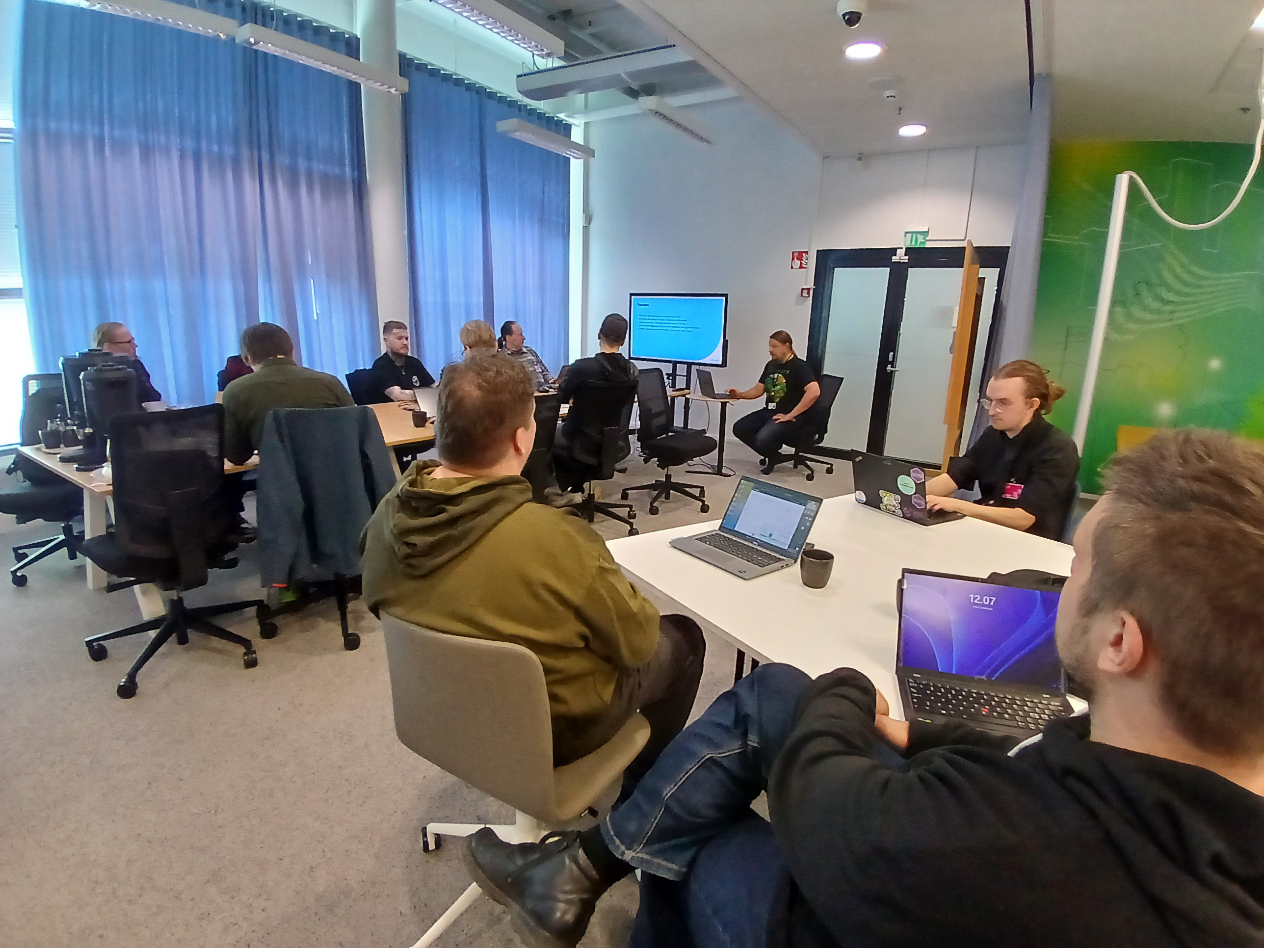A photograph where participants of the event listen to a presentation about updating Oskari.